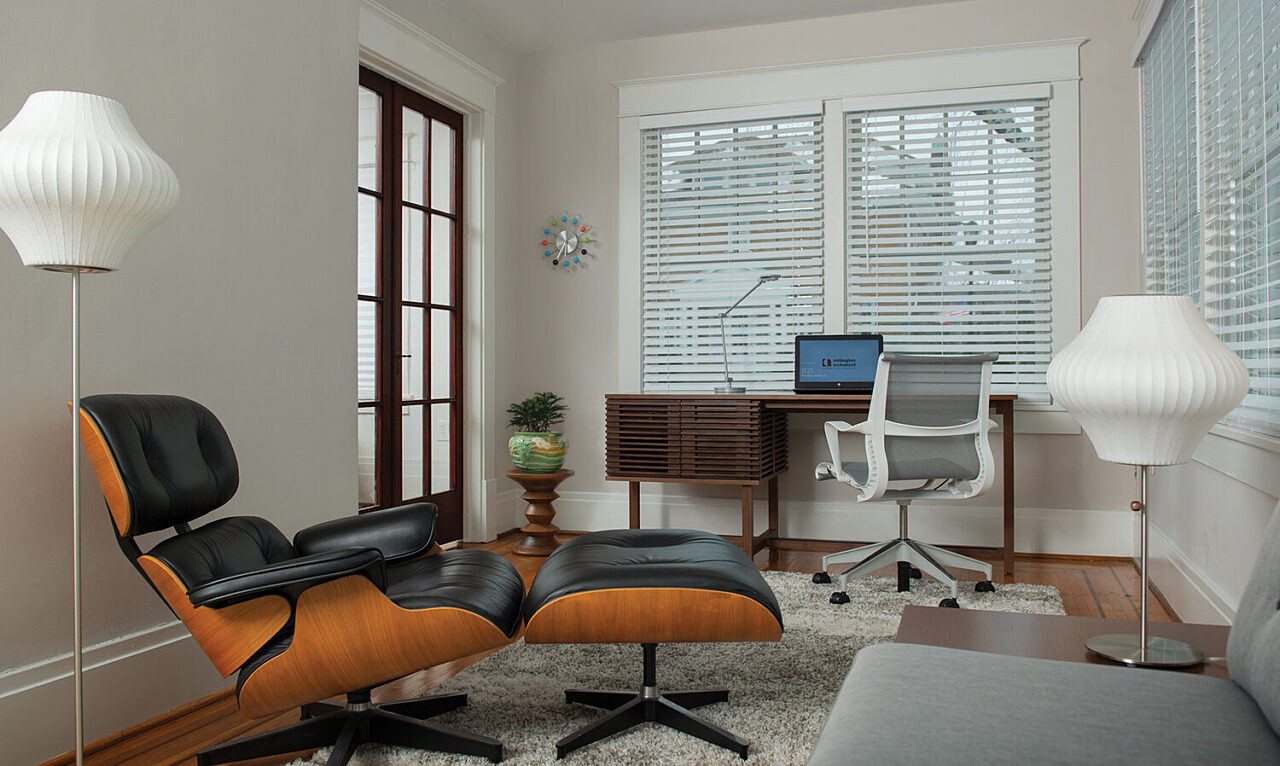 Picture of a well lit home office setting with walnut desk, performance seating chair and classic lounge chair and lamps