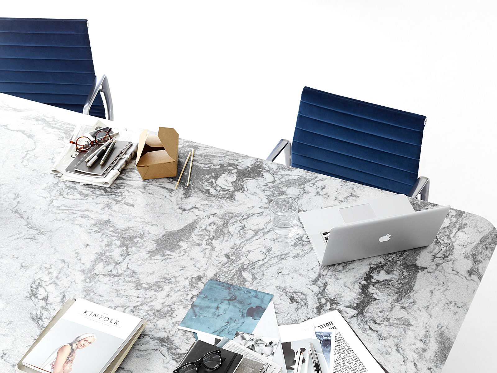 white and grey marble table with work materials such as notebooks on it.